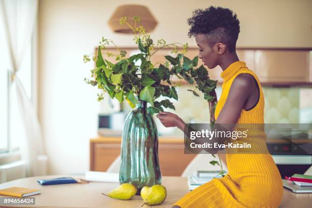 junge frau zu hause - blumenvase stock-fotos und bilder