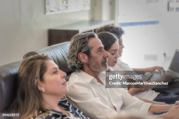 worried man with carefree family in living room - lypsesp17 stock pictures, royalty-free photos & images