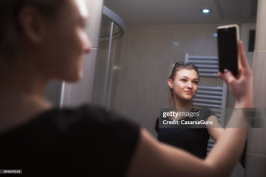 Beautiful Teenage Girl Taking a Selfie in Bathroom