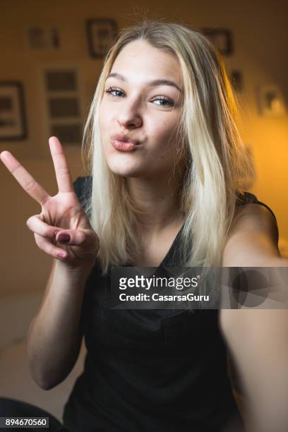 hermosa chica adolescente alegre tomando un selfie en dormitorio - morro fotografías e imágenes de stock