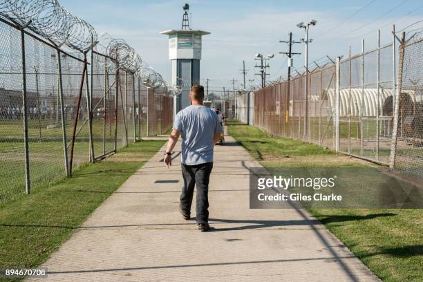 Prisoner walks thru a fenced section toward a guard tower at Angola Prison The Louisiana State Penitentiary, also known as Angola, and nicknamed the...
