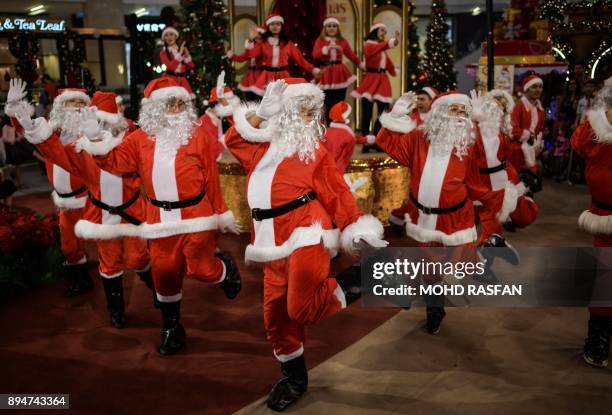 Performers clad in Santa Claus outfits dance at a shopping mall in Kuala Lumpur on December 18, 2017. Every year as Christmas approaches, shopping...