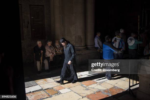 Priest passes visitors at the entrance of the Church of the Holy Sepulchre in the Christian quarter of the Old City in Jerusalem, Israel, on Sunday,...