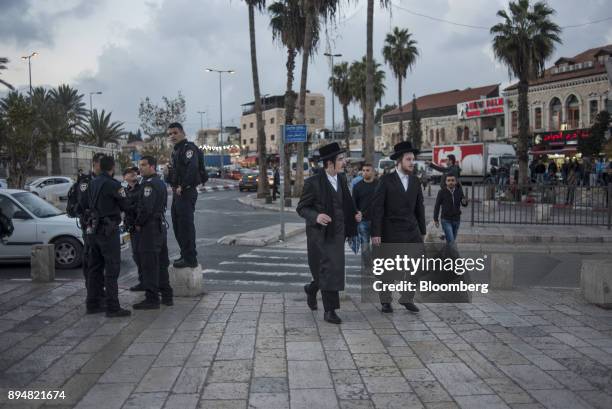 Two orthodox Jewish men walk past police officers near the Damascus Gate outside the Old City in Jerusalem, Israel, on Friday, Dec. 15, 2017. The...