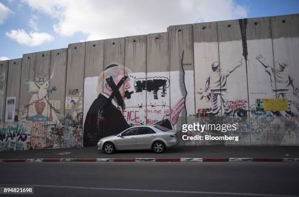 Black crosses deface the face of U.S. President Donald Trump in a graffiti mural on the Israeli West Bank security barrier wall at the Aida refugee...