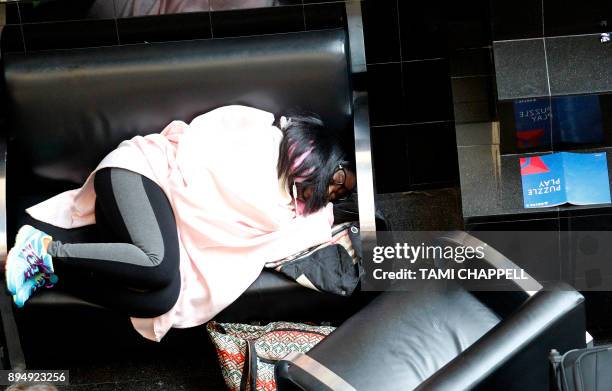 An airport passenger sleeps in the airport atrium as they wait on another flight the day following a power outage caused by a fire at...