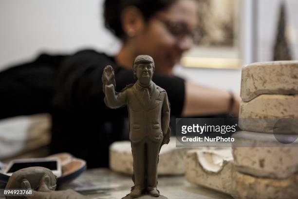 Giuseppina Erzingher works on a figurine Donald Trump in shop Ferrigno, in 'Via San Gregorio Armeno' in Naples, Italy on December 18, 2017. Various...