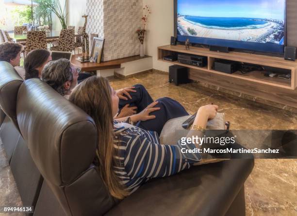 woman with remote control of the television with the family in the living room at leisure time - lypsesp17 stock pictures, royalty-free photos & images