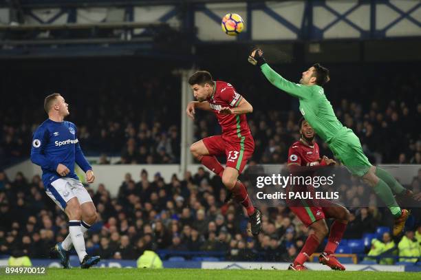 Swansea City's Polish goalkeeper Lukasz Fabianski punches the ball clear as Everton's English striker Wayne Rooney watches during the English Premier...