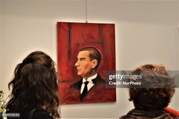 Women look at a painting of Mustafa Kemal Ataturk, founder and the first president of modern Turkey, during the opening of the 'Human Creation' Art...