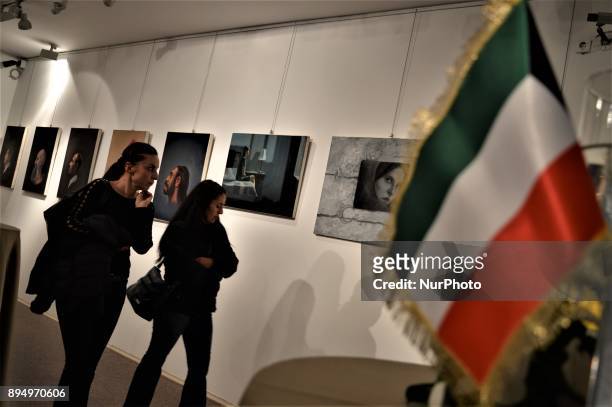 Kuwaiti flag is displayed while women walk past paintings during the opening of the 'Human Creation' Art Exhibition in Ankara, Turkey on December 18,...