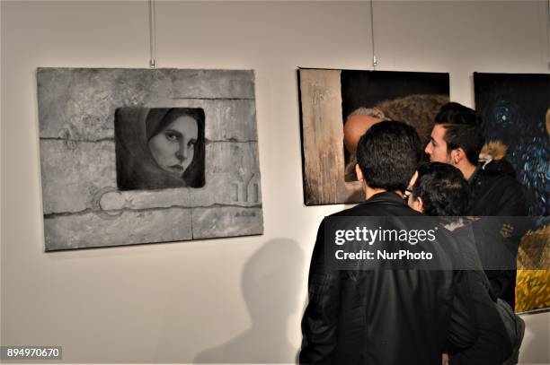 Young men look at paintings during the opening of the 'Human Creation' Art Exhibition in Ankara, Turkey on December 18, 2017. The exhibition, which...