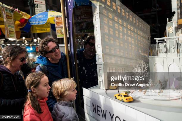 Family views a holiday display in the window of Lord & Taylor in Midtown Manhattan, December 18, 2017 in New York City. The city is decked out in...