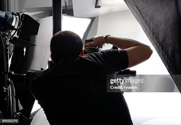 fotografo professionista da dietro guardando attraverso il mirino in studio - fotografo foto e immagini stock