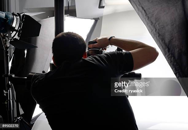 professional photographer from behind looking through viewfinder in studio - spiegelreflexcamera stockfoto's en -beelden
