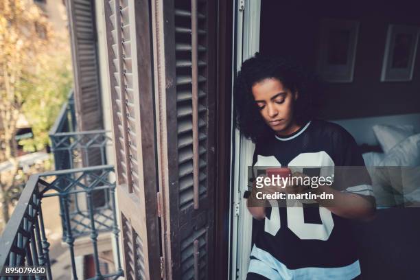 unhappy woman texting at the balcony - housing difficulties stock pictures, royalty-free photos & images