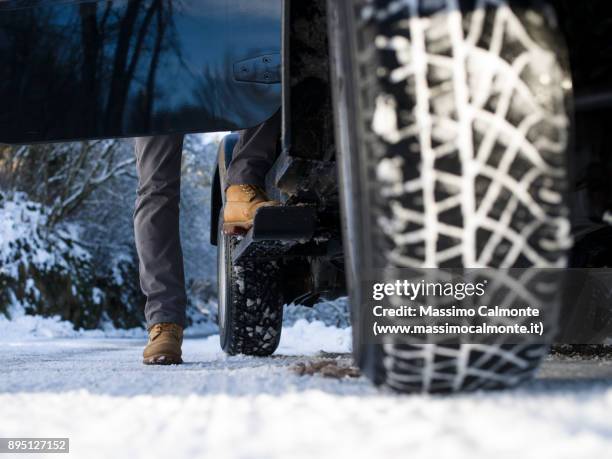 ground view of a jeep tyre on a snow-covered road - winter panne auto stock-fotos und bilder