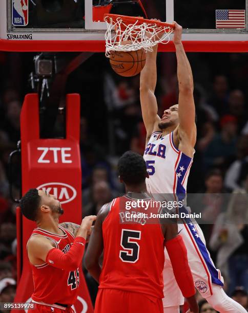 Ben Simmons of the Philadelphia 76ers dunks over Denzel Valentine and Bobby Portis of the Chicago Bulls at the United Center on December 18, 2017 in...