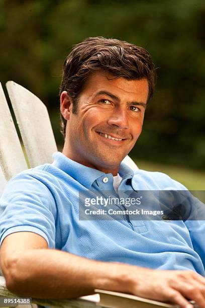 man sitting in adarondack chair - adirondack chair closeup stock pictures, royalty-free photos & images