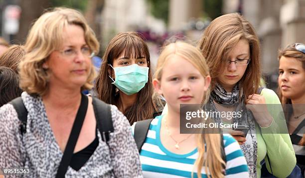 Woman wearing a surgical mask to prevent the transmission of airborne infection walks in Westminster on July 30, 2009 in London, England. Figures...