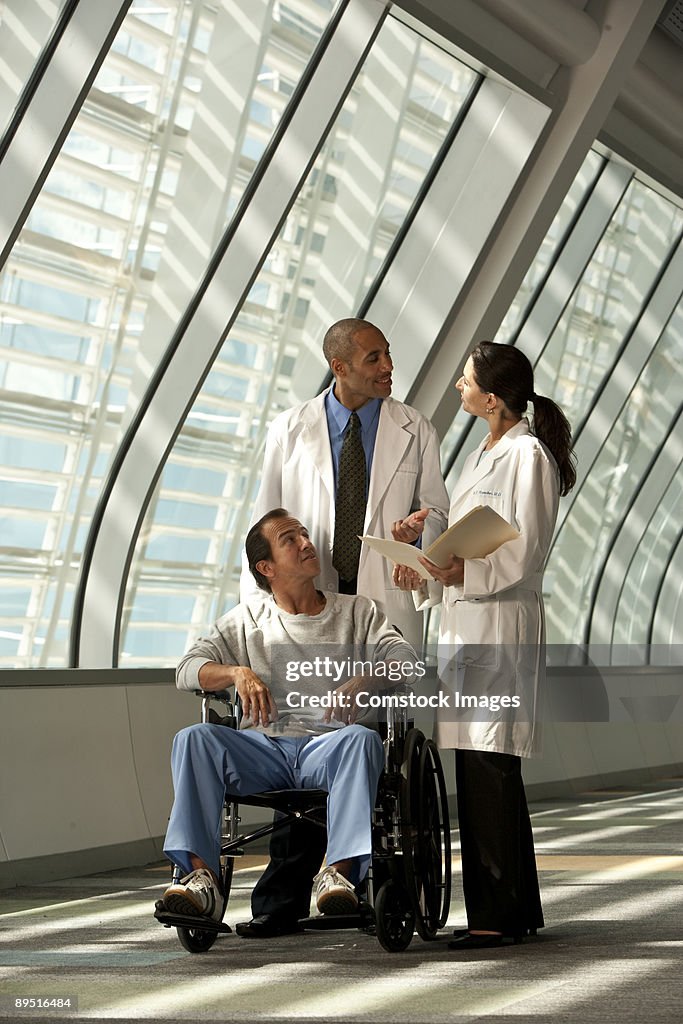 Two doctors with man in wheelchair