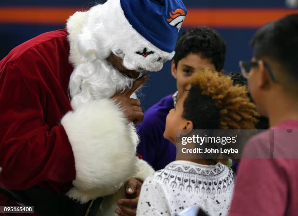 Santana Jones looks up at Santa Claus played by wide receiver Demaryius Thomas as he tells him not to blow his cover during the Denver Broncos...