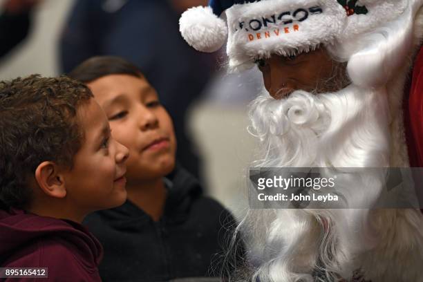 Santa Claus played by wide receiver Demaryius Thomas listens to Isaiah Jones and Abraham Herrera as they tell what they want for Christmas during the...