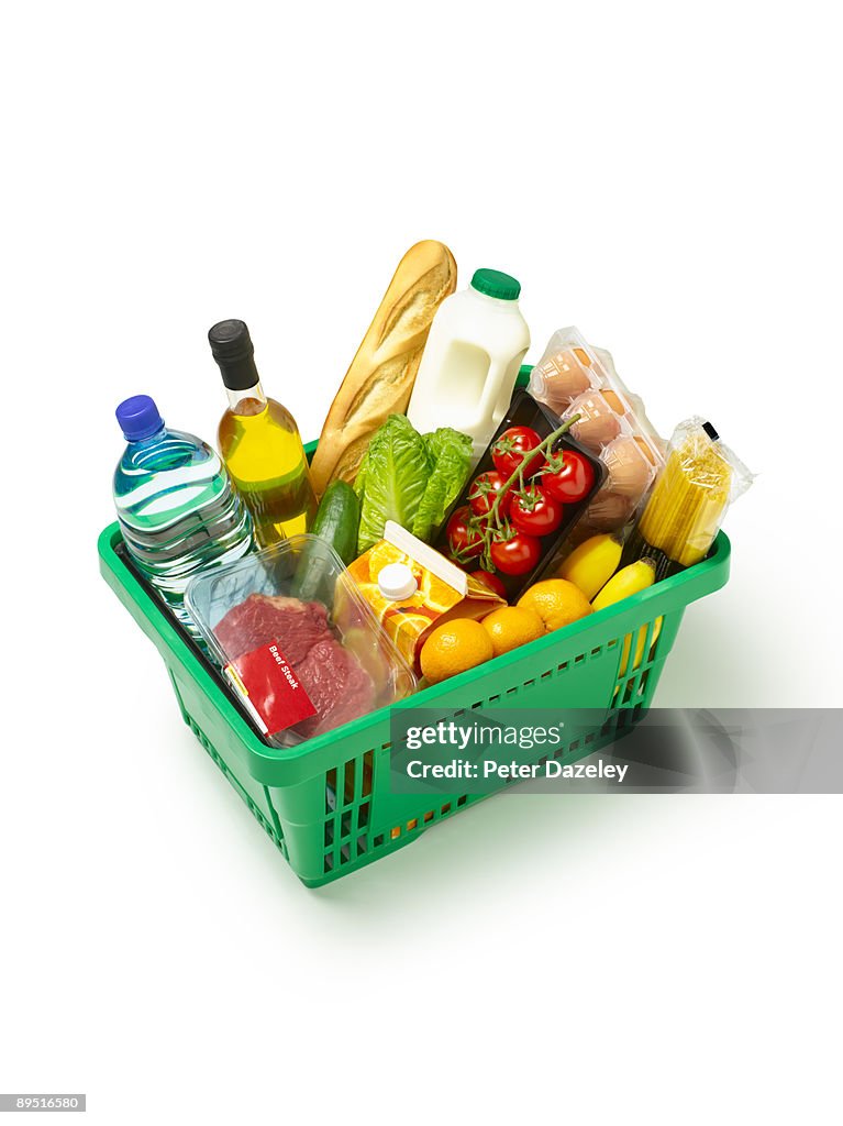 Supermarket basket with organic produce on white.