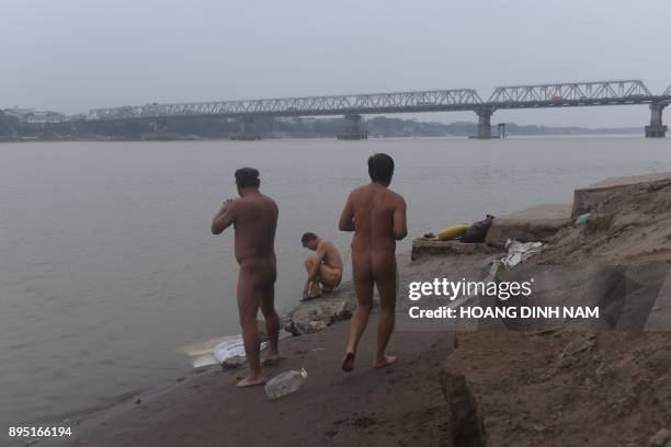 This picture taken on December 11, 2017 shows nudists preparing for a swim by the southern banks of the Red River in Hanoi. Butt cheeks bared,...