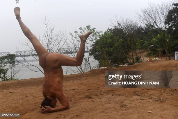 This picture taken on December 11, 2017 shows a nudist warming up for a swim by the southern banks of the Red River in Hanoi. Butt cheeks bared,...