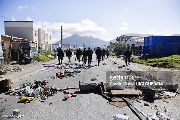 South African policemen walk on July 30, 2009 through burning rubbish firing rubber bullets to disperse a crowd of several hundreds of backyard...