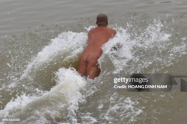 This picture taken on December 11, 2017 shows a nudist jumping into the Red River for a swim in Hanoi. Butt cheeks bared, Hanoi's ragtag nudist club...