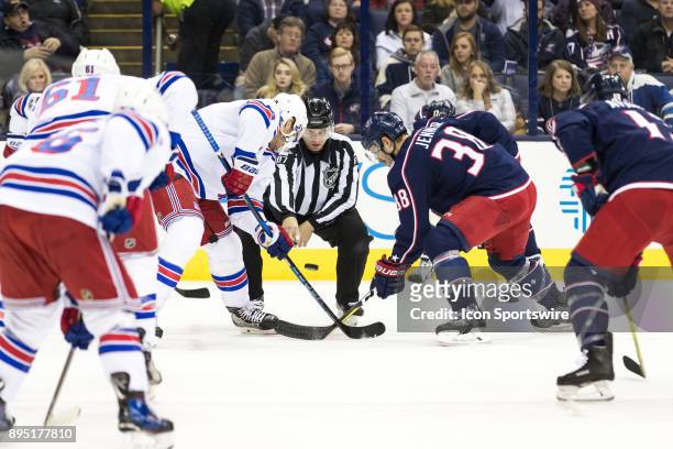 Linesman Devin Berg drops the puck for a face-off with New York Rangers center Paul Carey and Columbus Blue Jackets center Boone Jenner during a game...