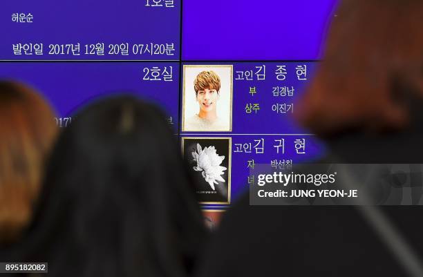 Tearful fans watch the portrait of Kim Jong-Hyun, a 27-year-old lead singer of the massively popular K-pop boyband SHINee, on an electronic board...