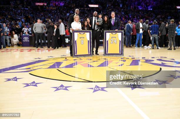 Kobe Bryant poses with his family and Earvin Johnson, Rob Pelinka and Jeanie Buss at halftime after both his and Los Angeles Lakers jerseys are...