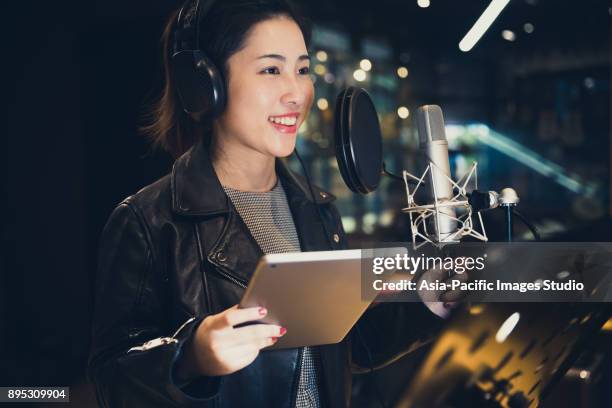 chica cantando y sostiene una tableta digital en un estudio de grabación, shanghai, china - micrófono de condensador fotografías e imágenes de stock