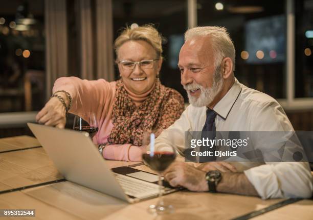 glücklich senioren surfen im internet zusammen. - wine glass finger food stock-fotos und bilder