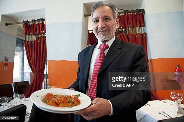 Ahmed Aslam Ali, the owner of the Shish Mahal restaurant in Glasgow, is pictured with a plate of Chicken Tikka Masala in his restaurant, on July 29,...