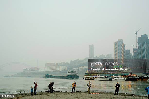 People looking up at some kite flying on the air on Chaotianmen beach, in Chongqing. The city of Chongqing is one of the fastest-growing urban...