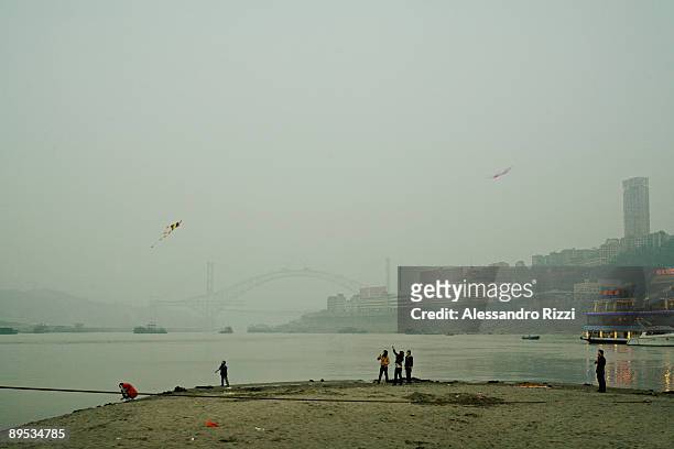 People looking up at some kite flying on the air on Chaotianmen beach, in Chongqing. The city of Chongqing is one of the fastest-growing urban...