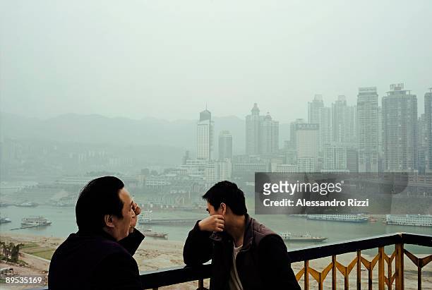 Two men look at the view from the lift station, near the Grand Theatre, in Chongqing. The city of Chongqing is one of the fastest-growing urban...