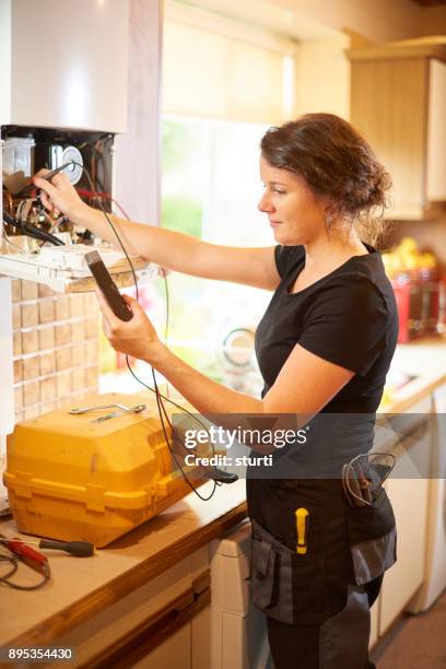 female heating engineer servicing a boiler - boiler engineer stock pictures, royalty-free photos & images