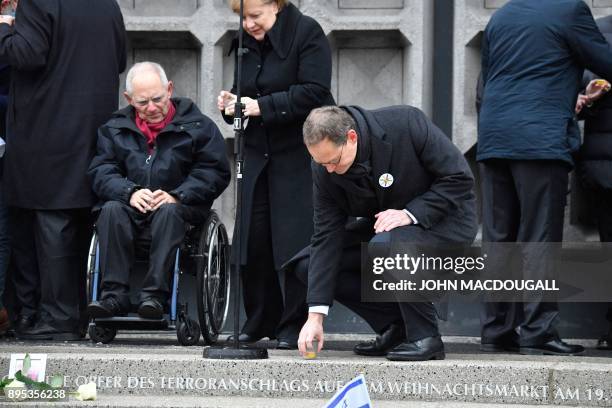 Berlin's mayor Michael Mueller places a candle on the memorial as German Chancellor Angela Merkel and the President of the Bundestag Wolfgang...