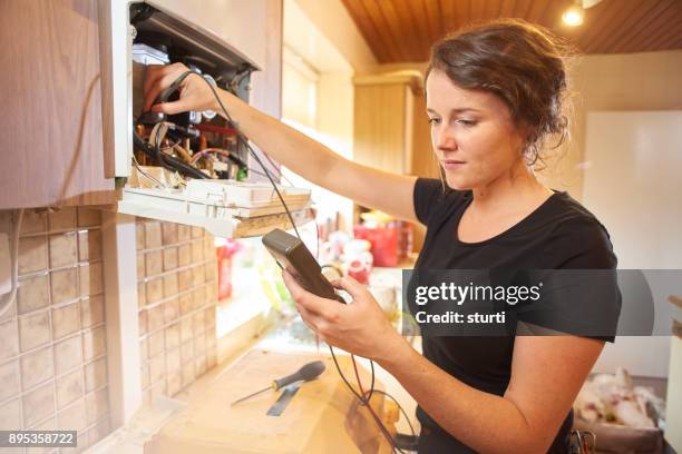 female plumber repairing a boiler - female electricians stock pictures, royalty-free photos & images