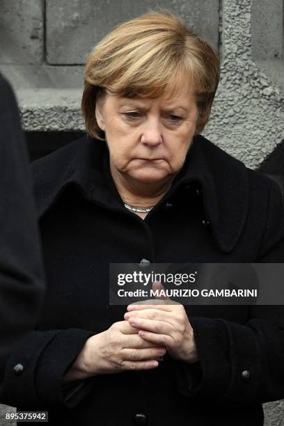 German Chancellor Angela Merkel holds a candle during the inauguration of the memorial for the victims of last year's deadly truck attack at the...