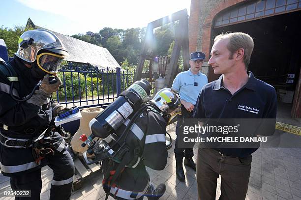 The director of the Cornille-Havard foundry Paul Bergamo looks at French firefighters before inspecting the foundry in the Normandy town of...