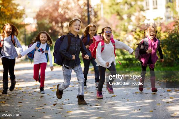enfants de l’école en cours d’exécution dans la cour d’école - première rentrée scolaire photos et images de collection