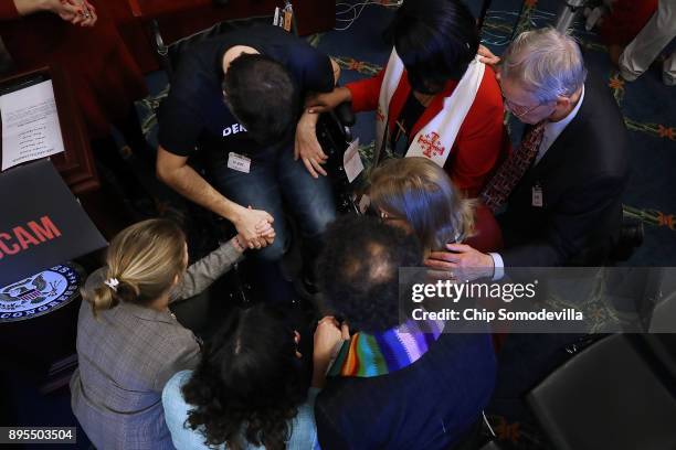 Ady Barkan, who lives with Amyotrophic Lateral Sclerosis, prays with faith leaders following a rally against the GOP tax bill in the Rayburn Room at...