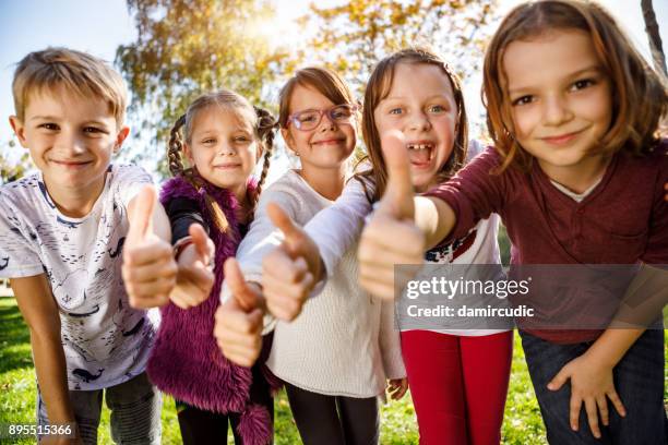 gruppe von kindern geben daumen nach oben - kids interacting in the classroom stock-fotos und bilder