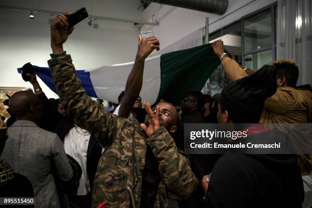 Group of men celebrate waving a national flag of Sierra Leone during the 3rd edition of Miss Africa Italy, on December 16, 2017 in Milan, Italy. Miss...